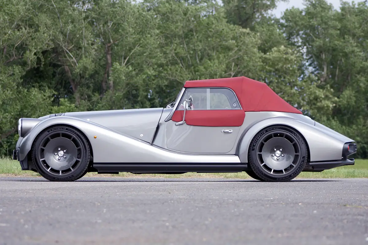 Seitenprofil des geschlossenen Morgan Supersport mit seinem roten, einlagigen Stoffverdeck.