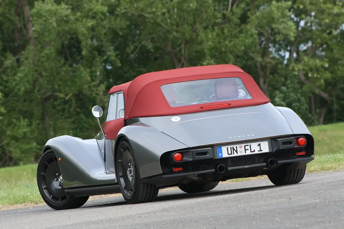 Heckansicht des silbernen Morgan Supersport mit geschlossenem roten Stoffdach und dem Kennzeichen UN FL 1.