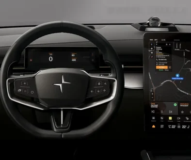 Blick auf das minimalistische, schwarze Cockpit eines Polestar-Elektrofahrzeugs mit digitalem Kombiinstrument hinter dem Dreispeichen-Lenkrad und einem großen, vertikalen Infotainment-Touchscreen, der eine aktive Navigationskarte anzeigt.