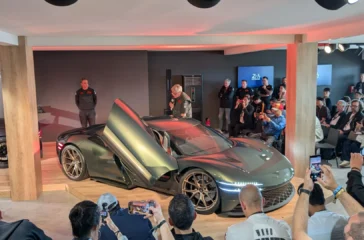 Die feierliche Weltpremiere des Genesis Magma GT Concept vor Publikum in Le Mans, präsentiert auf einer Ausstellungsbühne mit weit nach oben geöffneten Flügeltüren.