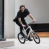 Ein Mann im schwarzen Outfit fährt sportlich mit dem weißen 20-Zoll-Kompaktrad Schindelhauer Neo über eine Betonstufe im urbanen Raum.