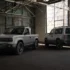 Der graue, unlackierte Slate Elektro-Pick-up als kompakter Zweitürer (links) und die längere, fünfsitzige Slate SUV-Variante mit aussen am Heck montiertem Ersatzrad (rechts) parken nebeneinander in einer historischen, hellen Industriehalle.