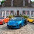 Drei Generationen von Alpine-Sportwagen – ein moderner orangefarbener A110, eine blau-schwarz lackierte A110 R Ultime und ein klassischer gelber Oldtimer – stehen nebeneinander auf dem gepflasterten Vorplatz des barocken Schlosses Thunstetten.
