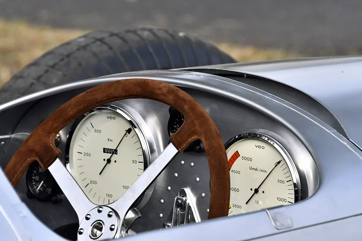 Nahaufnahme der spartanischen Kanzel des Auto Union „Lucca“ mit einem grossen, klassischen Holzlenkrad und zwei grossen analogen Rundinstrumenten im Armaturenbrett.