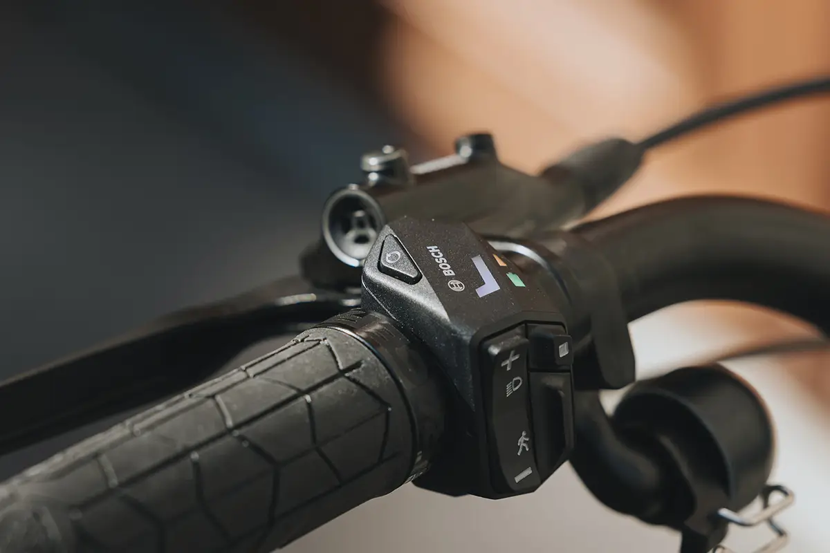 Nahaufnahme der neuen, am Fahrradlenker montierten Bosch LED Control Bedieneinheit, die per farbiger Lichtsignatur den Akkustand anzeigt und über einen integrierten USB-C-Anschluss verfügt.