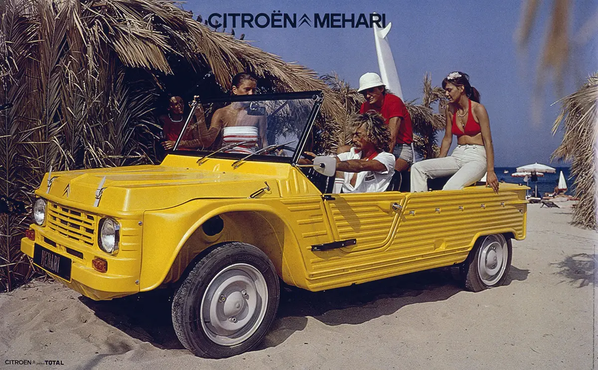 Yellow Citroën Méhari with open-top on a sandy beach, a group of people posing around the car on a sunny day.