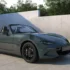Ein offener Mazda MX-5 Roadster des Modelljahrs 2027 mit der neuen, dunkelgrünen Metallic-Lackierung „Zinc Green“ und schwarzen Leichtmetallfelgen parkiert in einem minimalistischen Studio vor einer grauen Betonwand.