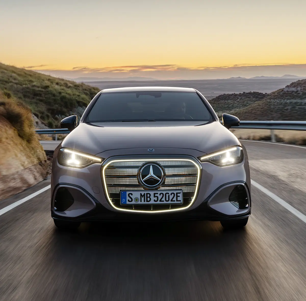 Frontalansicht des elektrischen Mercedes C 400 4Matic mit illuminierter Kühlermaske auf einer Landstrasse.