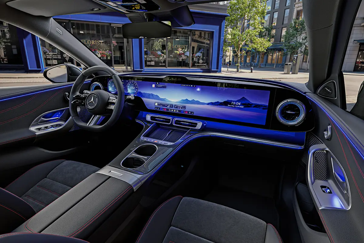 Cockpit der elektrischen Mercedes C-Klasse mit durchgehender Hyperscreen-Bildschirmlandschaft und blauer Ambientebeleuchtung.