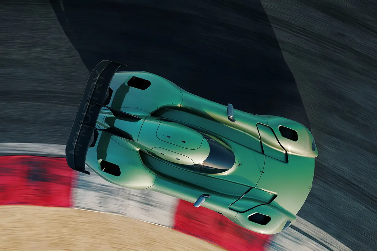 Der grüne McMurtry Spéirling Pure in dynamischer Kurvenfahrt auf den rot-weissen Curbs einer Rennstrecke, gestützt auf breite Michelin-Slicks und zwei Tonnen Abtrieb.