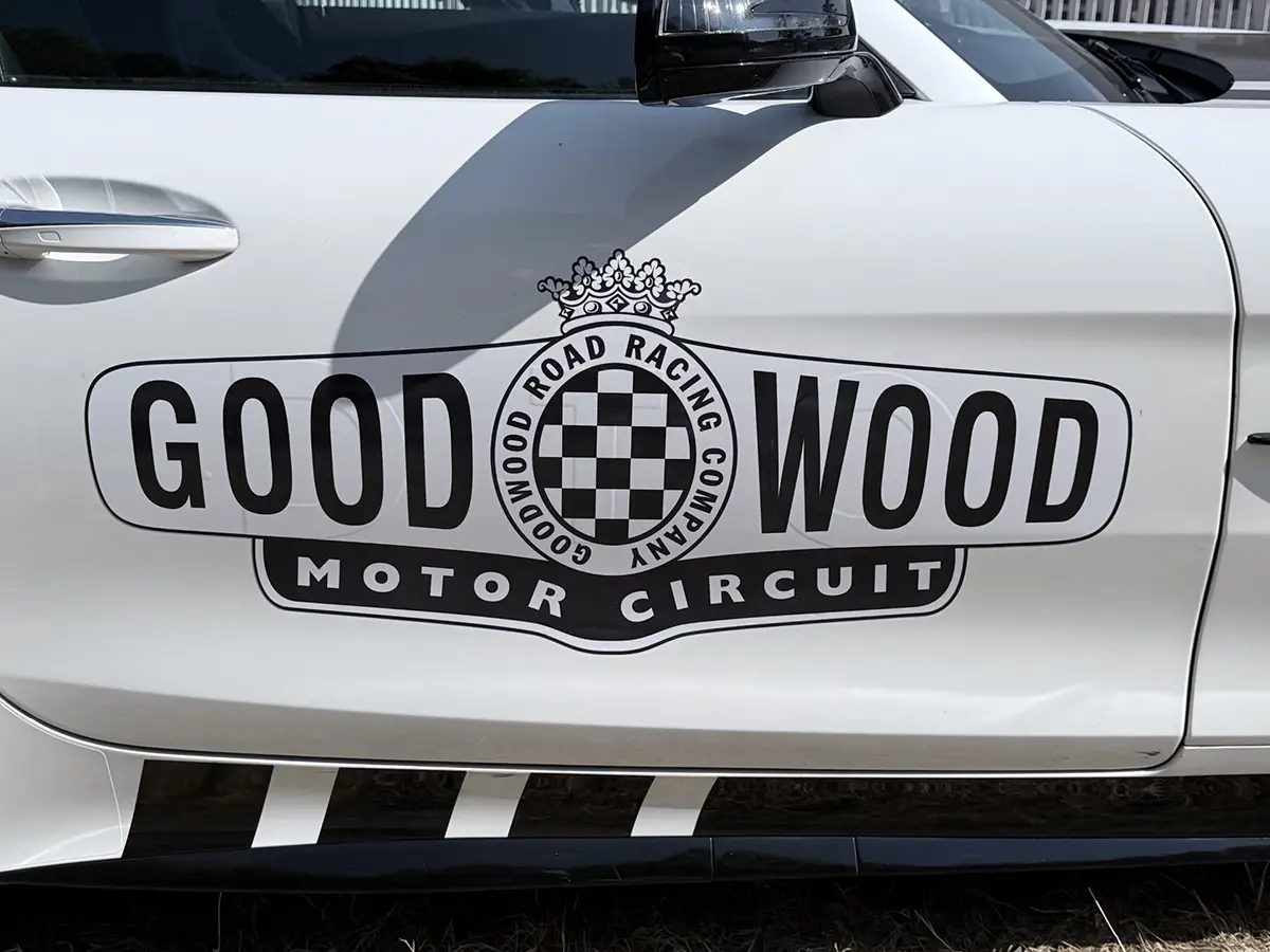 Nahaufnahme des offiziellen Emblems der Goodwood Road Racing Company - Motor Circuit auf der weißen Fahrertür eines Fahrzeugs.