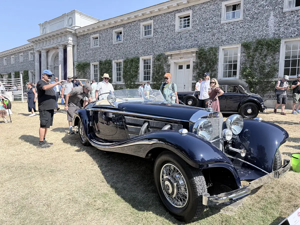 Ein historischer Vorkriegs-Luxus-Roadster parkt stilvoll im Außenbereich direkt vor dem imposanten Hauptgebäude des Goodwood Landsitzes.