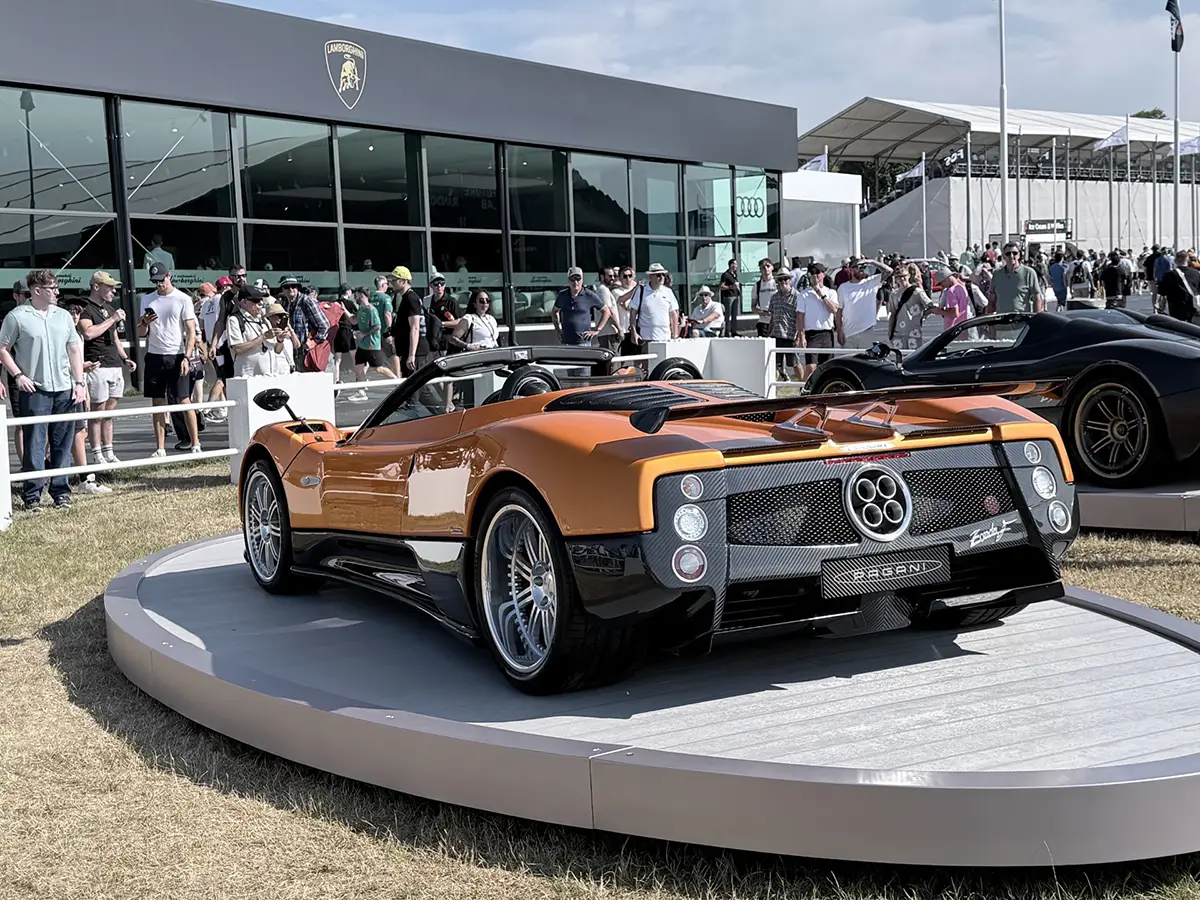 Das exklusive, orangefarbene Heck des Pagani Huayra 70 Derecho Hypersportwagens auf einer runden, erhöhten Ausstellungsplattform.