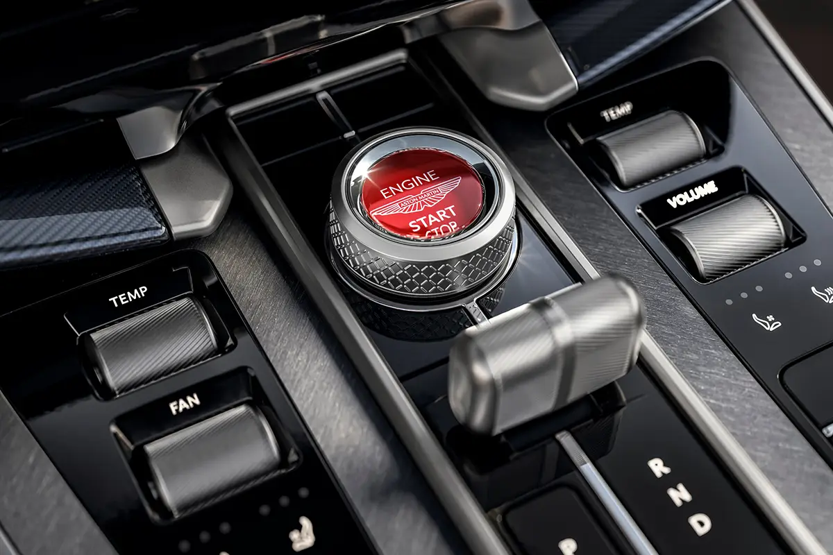 Nahaufnahme des roten Motor-Startknopfs in der Mittelkonsole des Aston Martin Vanquish 25 als Hommage an das Originalmodell von 2001.