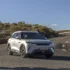 Ein silberner BYD Atto 2, ein kompaktes vollelektrisches Crossover-SUV aus chinesischer Produktion, fährt dynamisch auf einer asphaltierten Landstrasse im hellen Tageslicht.