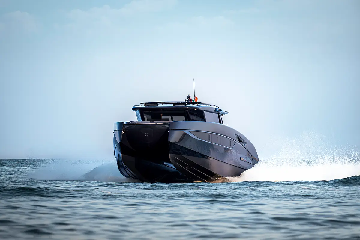 Frontalansicht des Luxuskatamarans BRABUS ULTIMA 55 bei schneller Fahrt, wobei sich die Rümpfe durch das Foiling-System leicht aus dem Wasser heben. Foto: Brabus