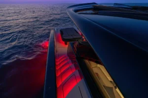 BRABUS Ultima 55: Luxuriöses Schnellboot auf dem dunkelblauen Meer in der Abenddämmerung mit roter Innenbeleuchtung im Sitzbereich. Foto: Brabus Luxury speedboat over dark blue sea at dusk with red interior cabin lighting along the seating area