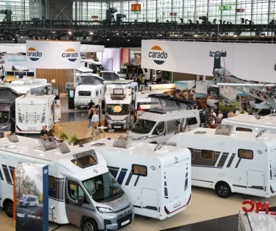 Blick von oben auf die Ausstellungsfläche des Caravan-Salons Düsseldorf mit mehreren modernen, weissen Reisemobilen, integrierten Wohnmobilen und Camper-Vans im Hallenbereich.