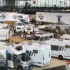 Blick von oben auf die Ausstellungsfläche des Caravan-Salons Düsseldorf mit mehreren modernen, weissen Reisemobilen, integrierten Wohnmobilen und Camper-Vans im Hallenbereich.