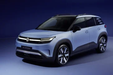 Schrägansicht von vorne auf das hellblaue Serienmodell des VW ID.Cross Elektro-Crossovers mit schmalen LED-Scheinwerfern und durchgehendem Leuchtenband im Fotostudio