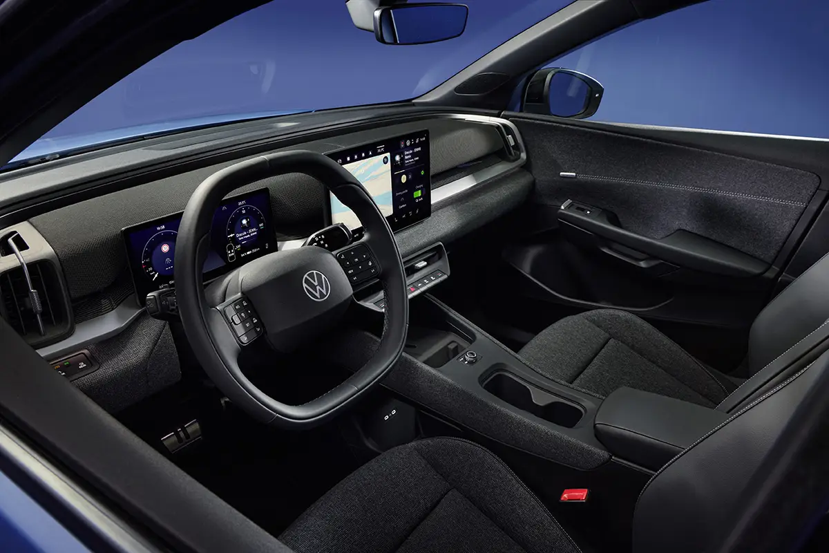 Blick von der Fahrerseite in den aufgeräumten, dunklen Innenraum des VW ID.Cross mit dem neuen Infotainment-Bildschirm und dem Multifunktionslenkrad.