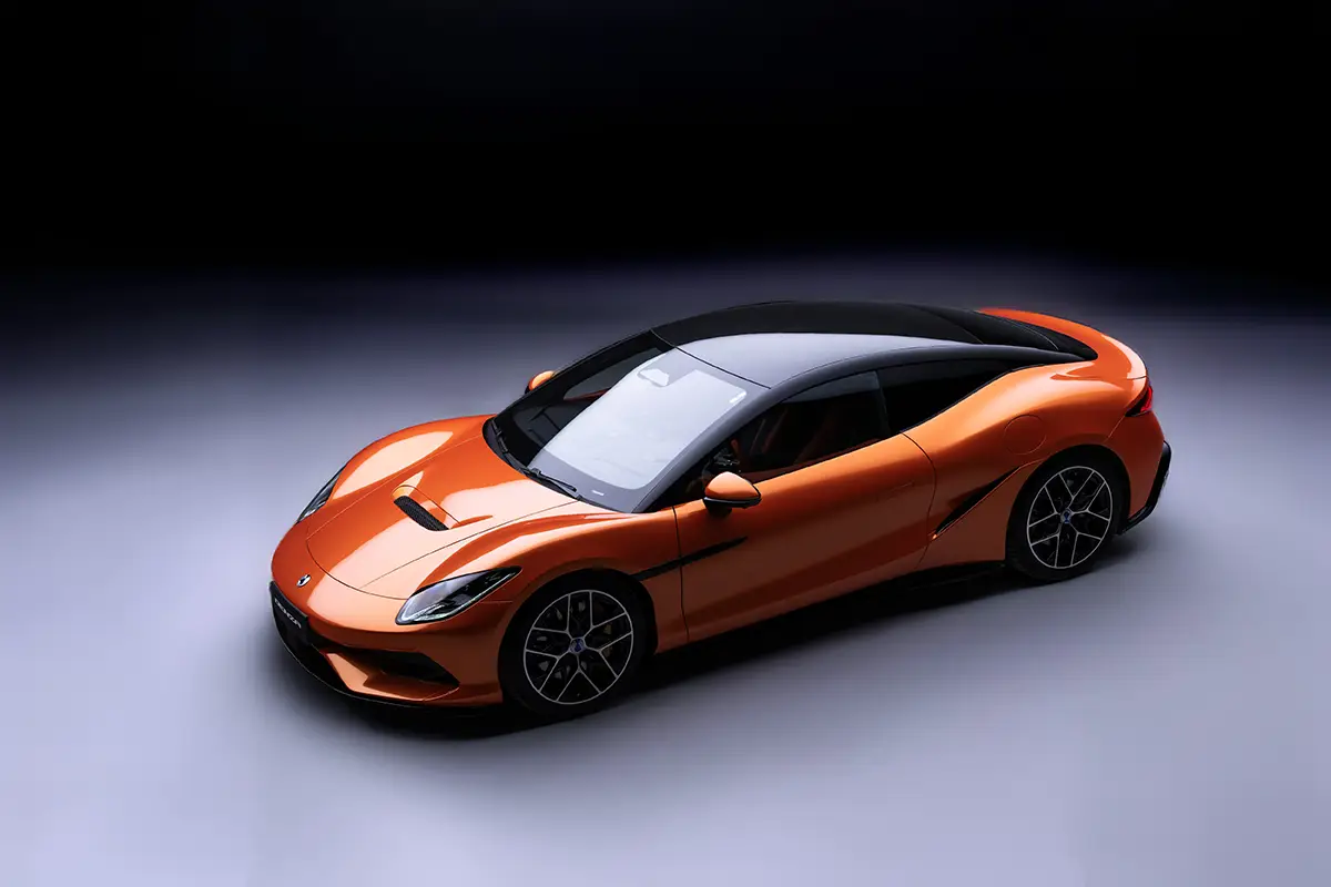 Draufsicht auf den orangefarbenen Denza Z von schräg oben, die das fliessende aerodynamische Design und das dunkle Glasdach des Coupés betont.