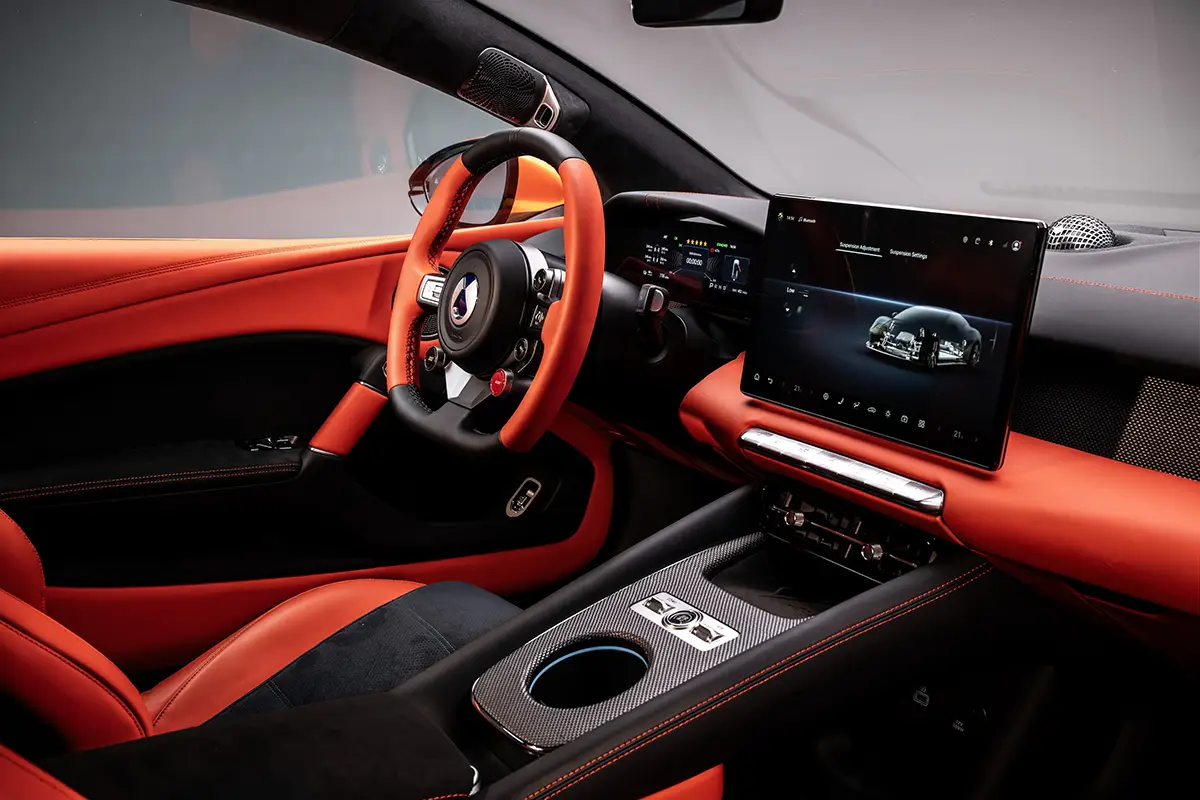 Blick in das Cockpit des Denza Z mit zweifarbigem (rot-schwarz) Sportlenkrad, digitalen Cockpit-Anzeigen, Carbon-Schalensitzen und einem grossen Infotainment-Bildschirm.