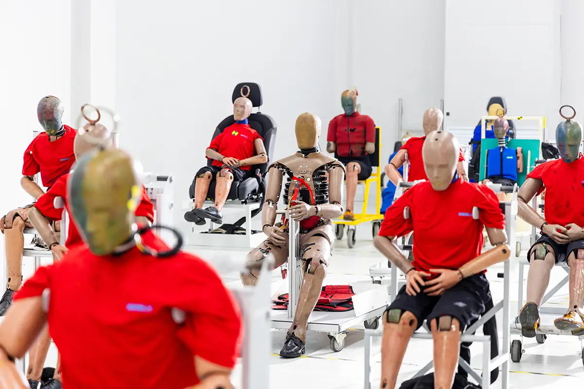 Zahlreiche mit Sensoren bestückte Crashtest-Dummies in roten Shirts warten auf Stühlen im Geely-Sicherheitslabor auf ihren Einsatz.