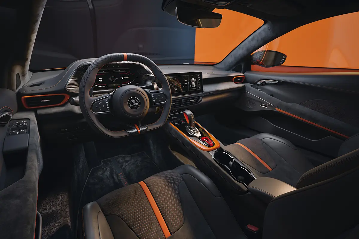 Der Innenraum des Lotus Emira 420 Sport zeigt ein sportliches Leder-Cockpit mit digitalen Displays und orangen Ziernähten.