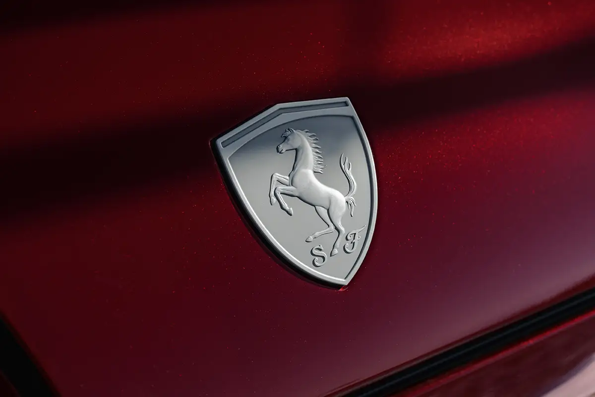 Nahaufnahme des markanten, silbernen Ferrari-Logos mit dem aufbäumenden Pferd (Cavallino Rampante) auf der dunkelroten Karosserie der Sonderserie.