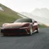 Ein tiefroter Ferrari 12Cilindri Manuale Supersportwagen in dynamischer Fahrt auf einer asphaltierten Bergstrasse vor einer hügeligen Ideallandschaft.