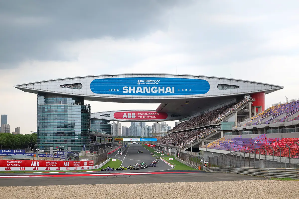 Die Start-Ziel-Gerade des Shanghai International Circuit während des Formel E Shanghai E-Prix 2026 unter bewölktem Himmel mit den Tribünen und dem markanten, die Strecke überspannenden Brückengebäude mit der Aufschrift Shanghai E-Prix.