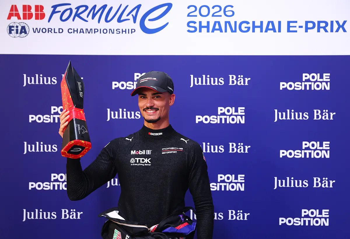 Pascal Wehrlein lächelt in der Boxengasse im schwarzen Porsche-Motorsport-Shirt mit Sponsorenlogos von Mobil und TDK und hält stolz die Julius Bär Pole Position Trophäe in der Hand.