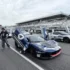 Zwei exklusive Maserati Rennsportwagen, darunter ein dunkelblauer GT2 Stradale mit nach oben geöffneten Flügeltüren, stehen in der Hockenheimring-Boxengasse beim ersten Master Maserati Auslandstraining.