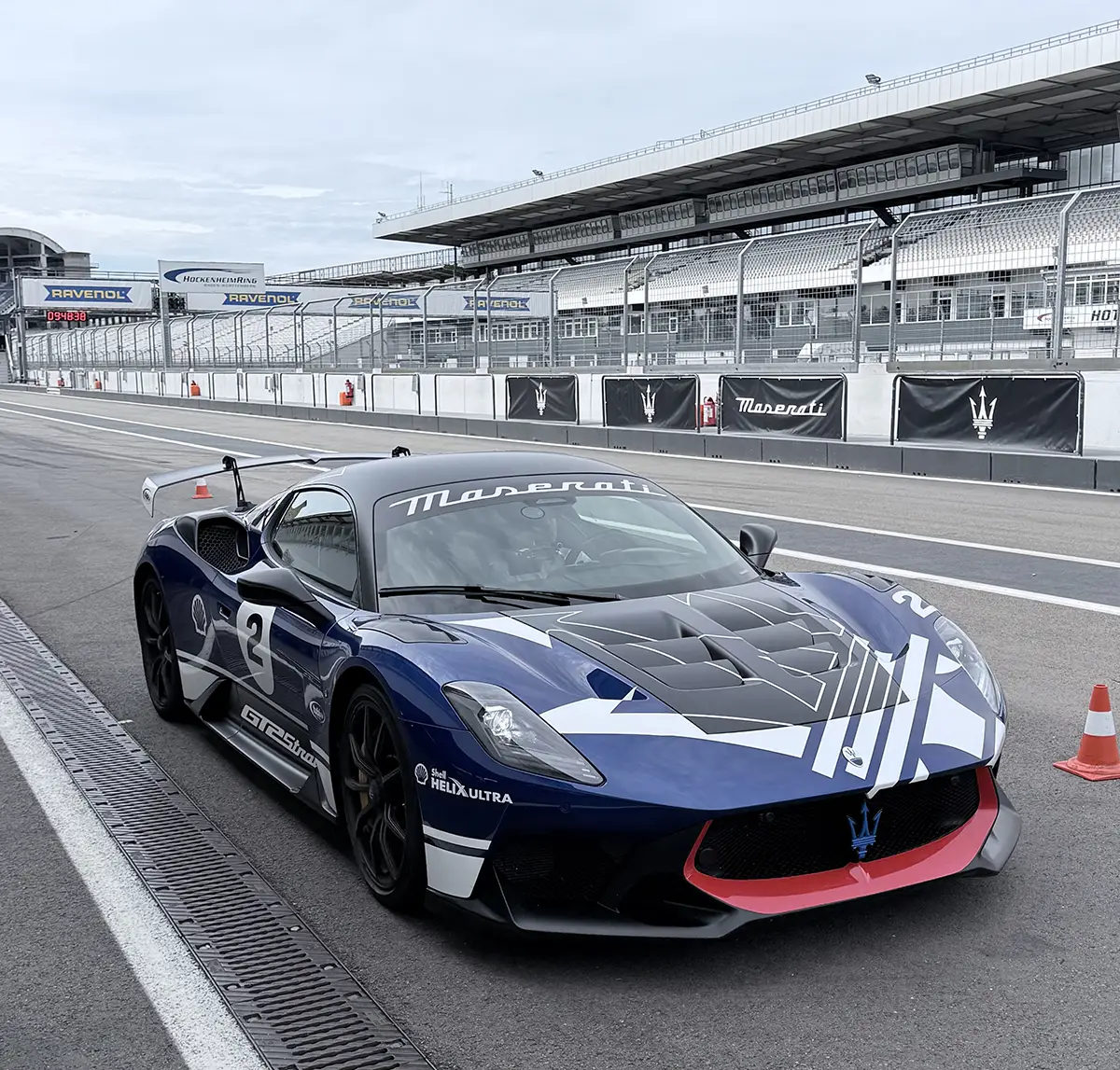 Dynamische Frontalansicht des dunkelblauen Maserati GT2 Stradale auf der Start-Ziel-Geraden des Hockenheimrings.