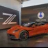 Ein flacher, sportlicher roter Denza Z Supersportwagen steht im BYD-Ausstellungspavillon vor einer Wand mit einem beleuchteten Marken-Logo beim Goodwood Festival of Speed 2026.