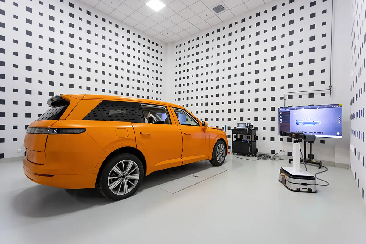 Ein oranges Elektro-SUV in einem Präzisionsmess- und EMV-Labor von Geely mit gepunkteter Wandverkleidung.