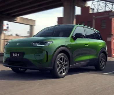 Ein moderner, giftgrüner Leapmotor B03X Elektro-Crossover steht im urbanen Raum auf einer Strasse unter einer Betonbrücke vor einem roten Backsteingebäude.