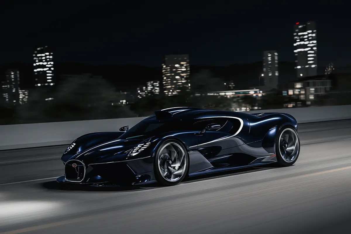 Der dunkelblaue Bugatti Destrier fährt nachts mit eingeschalteten LED-Scheinwerfern vor einer erleuchteten Skyline.