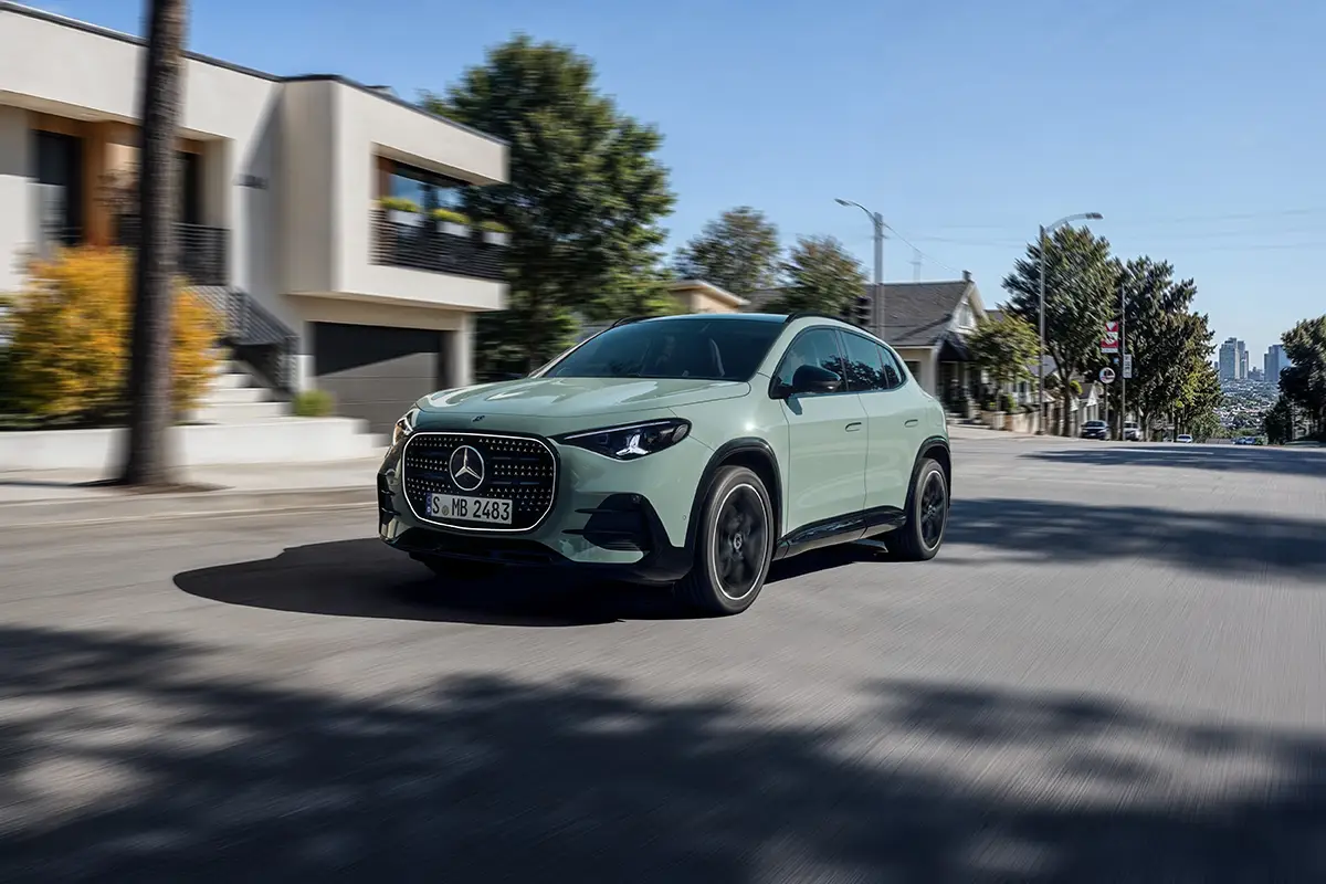 Hellgrüner Mercedes-Benz GLA Elektro-SUV fährt durch eine Wohnstrasse im Sonnenschein.