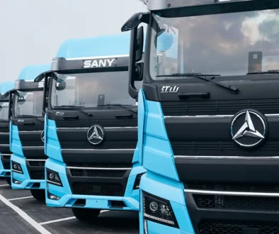 Eine Reihe hellblauer chinesischer Sany Elektro-Lkw parkiert auf einem Areal vor der Auslieferung an Flottenkunden.