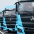 Eine Reihe hellblauer chinesischer Sany Elektro-Lkw parkiert auf einem Areal vor der Auslieferung an Flottenkunden.