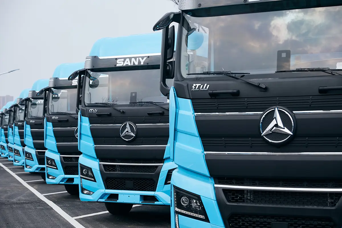 Eine Reihe hellblauer chinesischer Sany Elektro-Lkw parkiert auf einem Areal vor der Auslieferung an Flottenkunden.