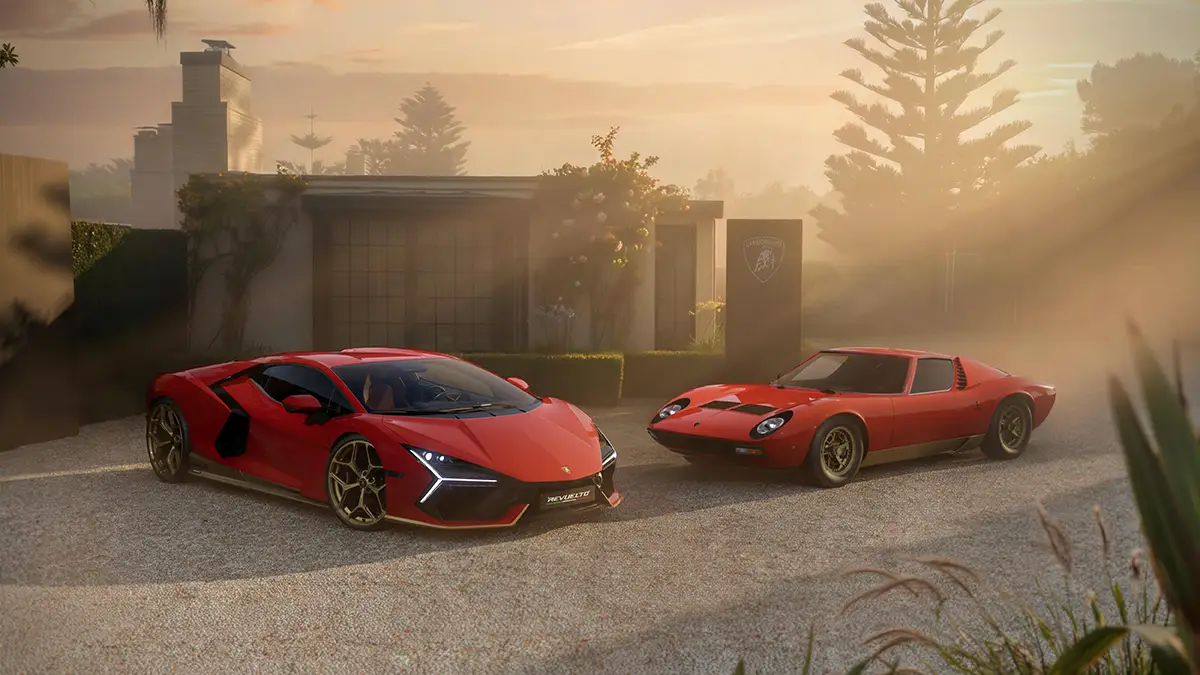 Ein roter Lamborghini Revuelto Sondermodell parkiert neben einem klassischen roten Lamborghini Miura aus den 1960er Jahren auf einem staubigen Landweg im warmen Abendlicht.
