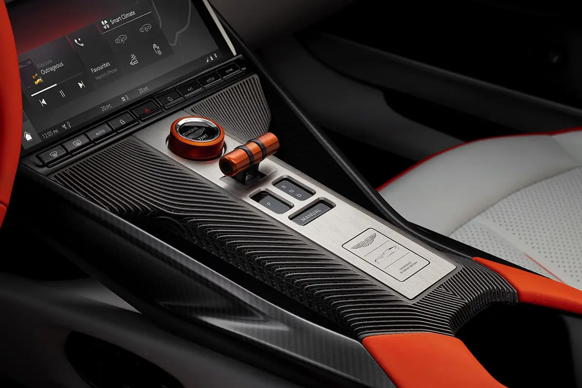 Nahaufnahme der zum Fahrer geneigten Mittelkonsole des Aston Martin Valen mit 3D-gedruckten Carbon-Elementen und roten Wahlschaltern.