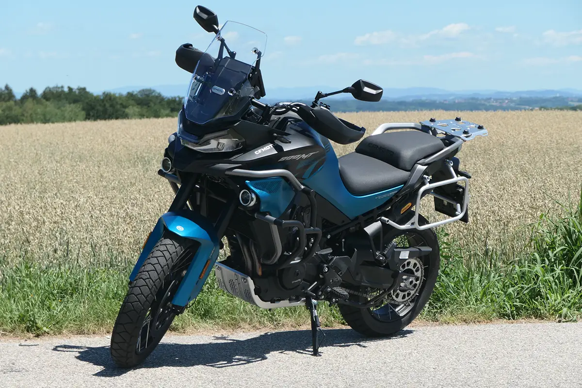 Seitenprofil der CF Moto 800 MT-ES Reiseenduro in Blaumetallic auf dem Seitenständer vor einem Feld.
