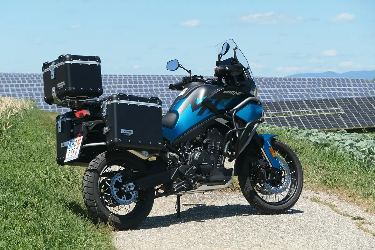 Heckseitenansicht der CF Moto 800 MT-ES mit montiertem dreiteiligen Aluminium-Koffersystem auf einem Weg.