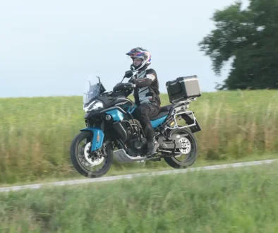 Fahrer auf der blauen CF Moto 800 MT-ES Reiseenduro mit Koffersystem beim Befahren eines Schotterwegs am Feldrain.