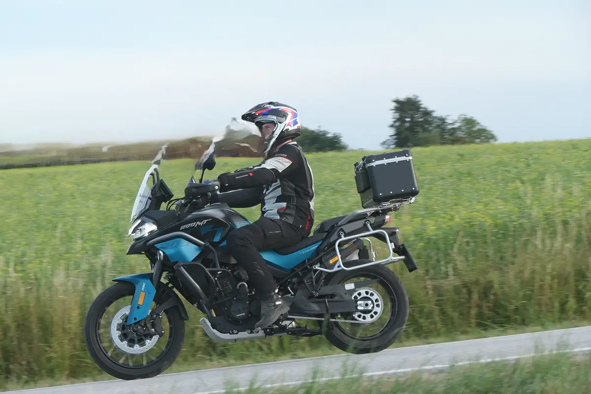 Seitenansicht der CF Moto 800 MT-ES auf einem Feldweg im Stand mit Fahrer im Enduro-Outfit.
