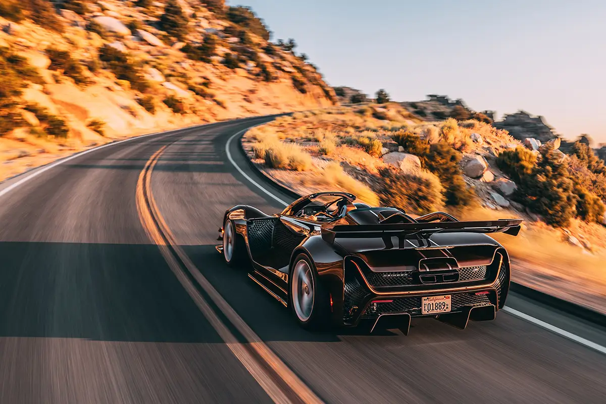 Heckansicht des Czinger 21C Spyder auf der Passstrasse mit sichtbarem Carbon-Heckflügel und breitem Diffusor.